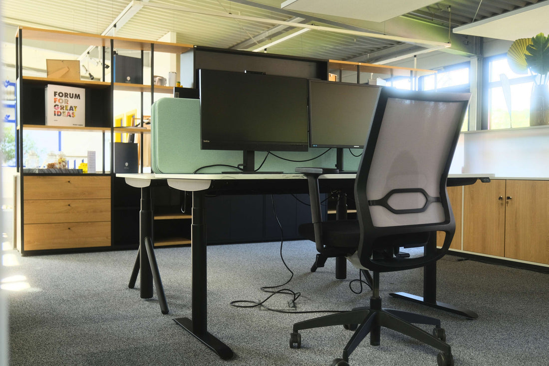 Zwei höhenverstellbare Arbeitsplätze mit Monitoren und Bürodrehstühlen