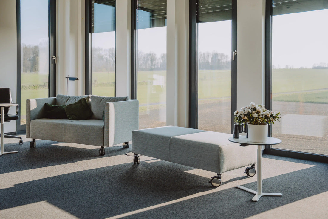 Sofa, Hocker und Beistelltisch vor einer bodentiefen Fensterfront