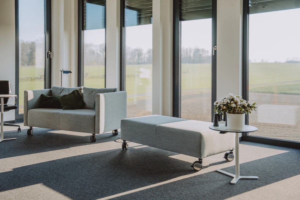 Sofa, Hocker und Beistelltisch vor einer bodentiefen Fensterfront