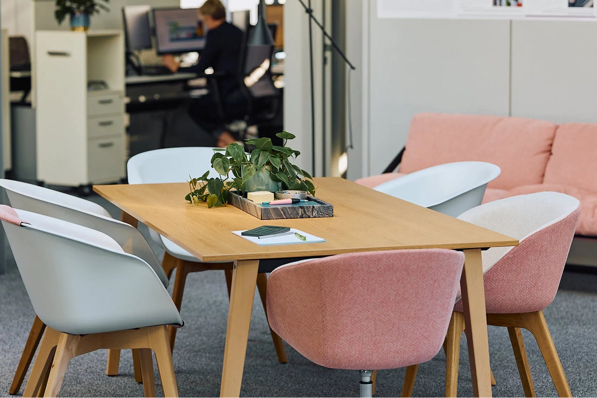Besprechungstisch mit pastellfarbenen Schalenstühlen in einem offenen Büro