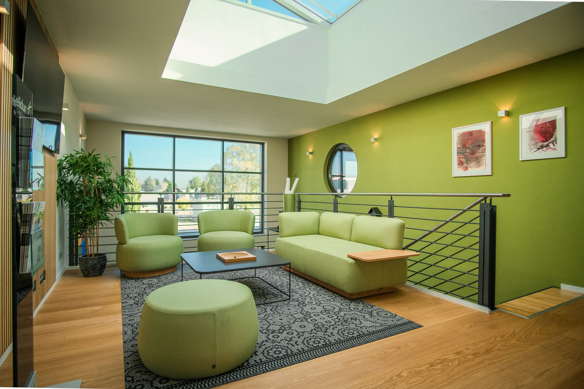 Lounge bei BAU 72 in Iffezheim: grüne Sofas, Sessel und Pouf unter dem Oberlicht