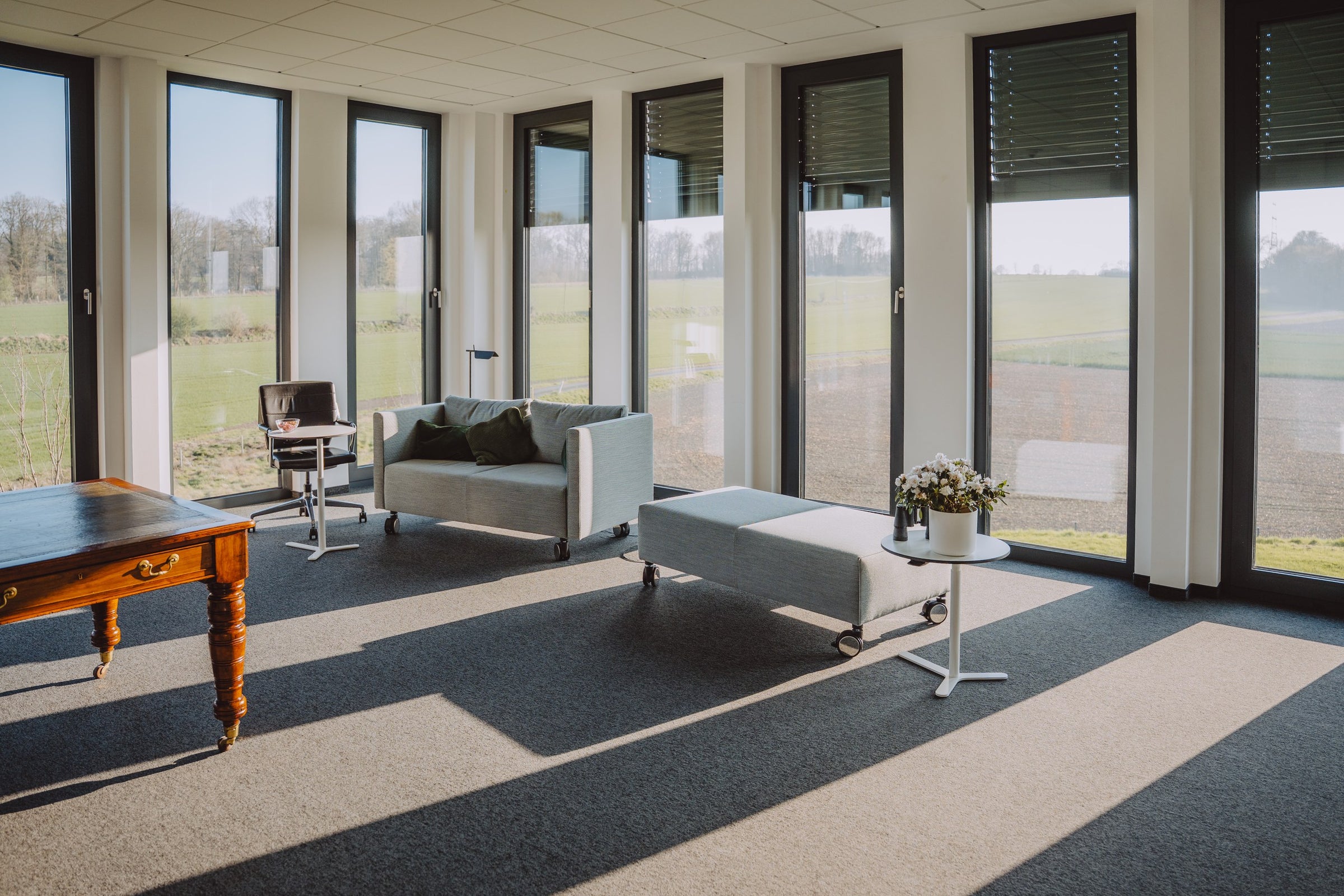 Bürolounge im Mönninghoff-Neubau mit Sofa, Polsterhocker und Panoramafenster