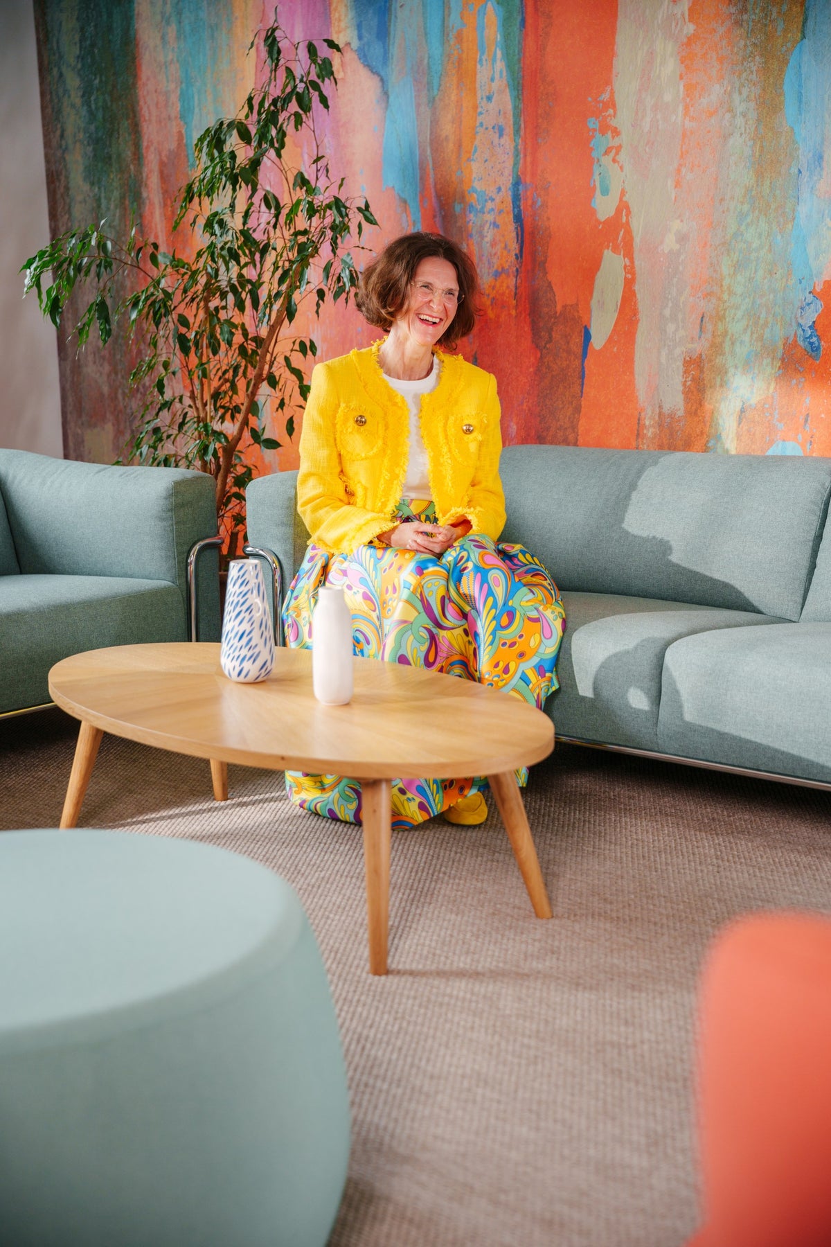 Frau auf dem Sofa der Sitzgruppe vor dem Wandbild im New-Work-Raum