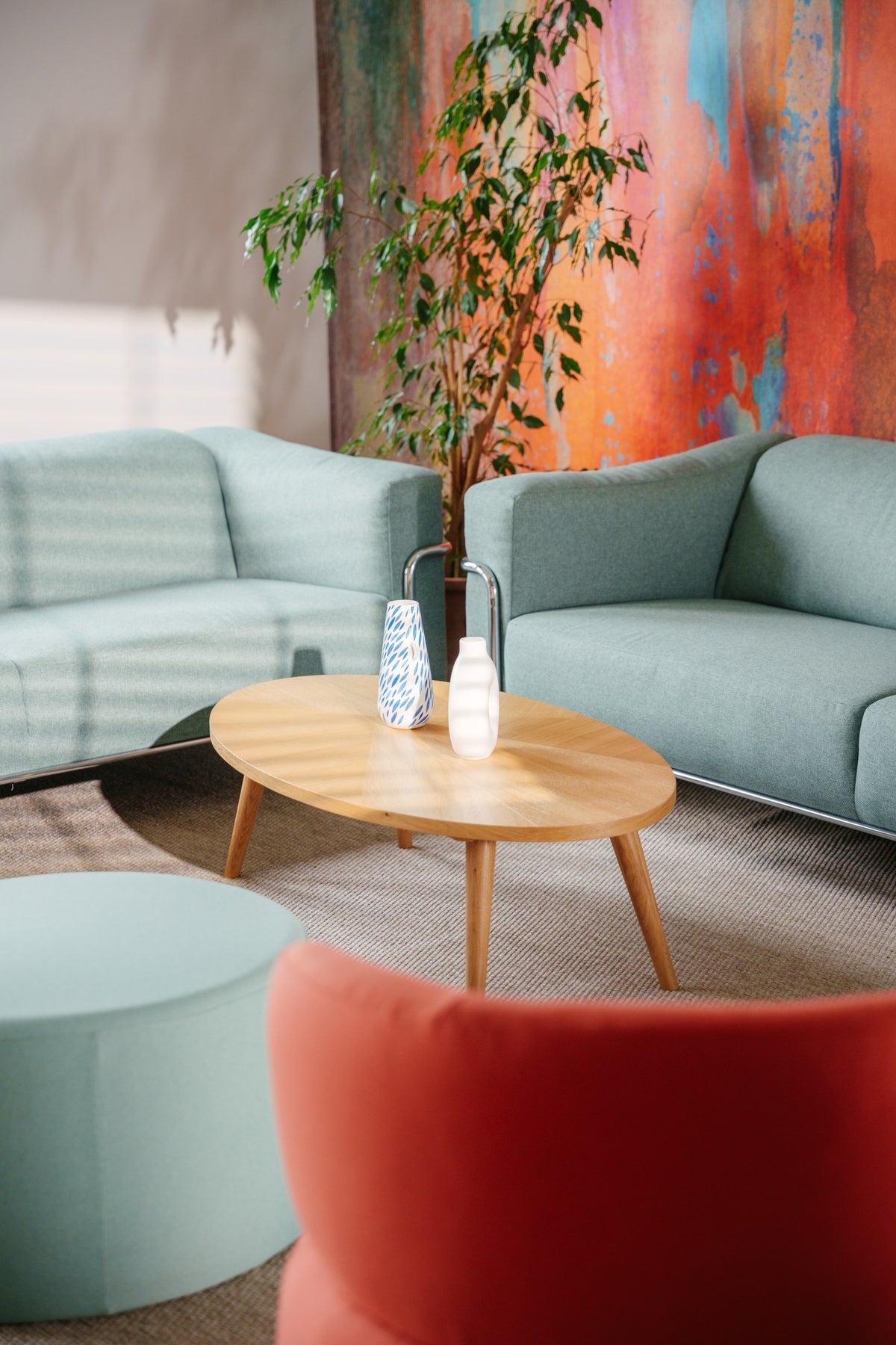 Sofa und Couchtisch vor dem Wandbild, Sitzhocker im Vordergrund