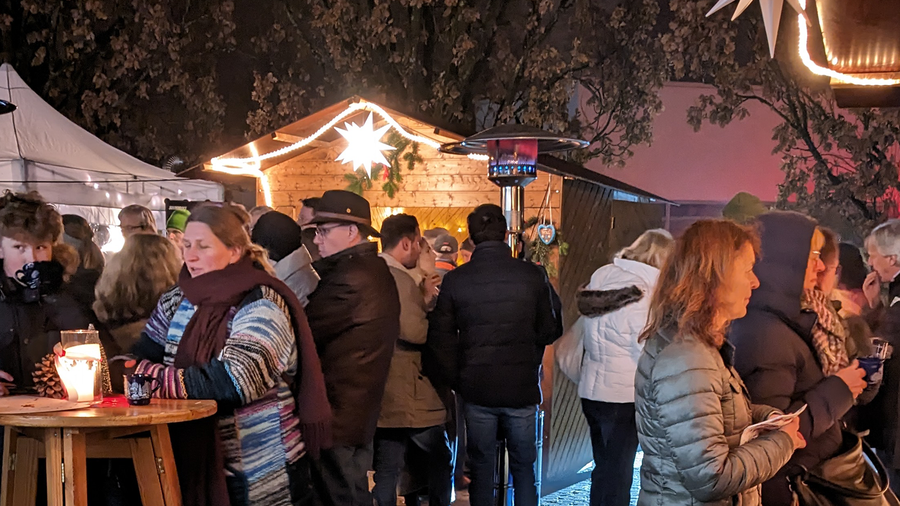 Gäste im Freien unter Lichterketten zwischen Pavillons und Heizstrahlern