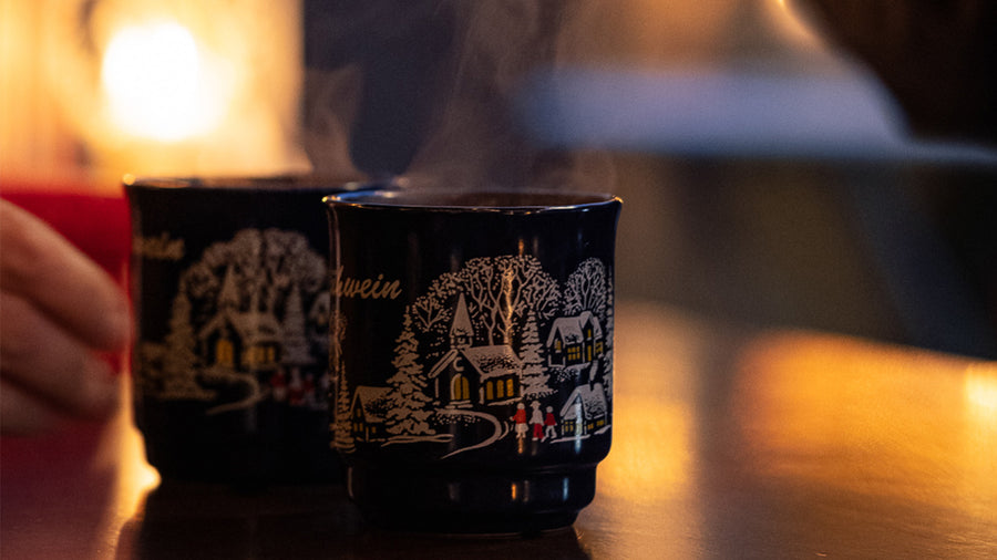 Zwei dampfende Glühweintassen mit Wintermotiv