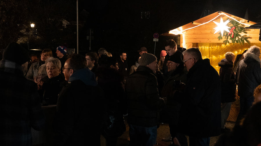 Viele Gäste vor der beleuchteten Hütte am Abend