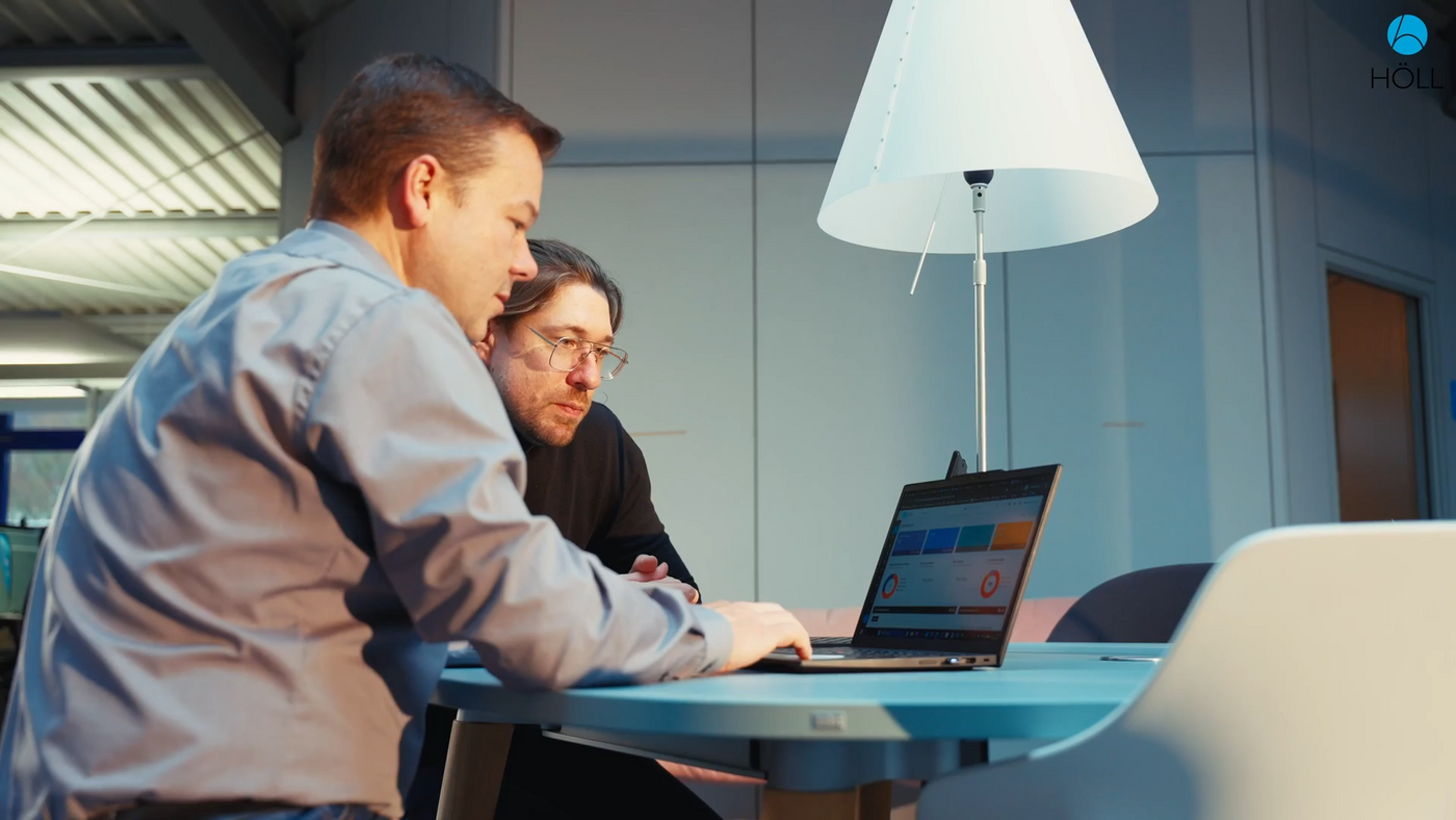 Zwei Mitarbeiter schauen gemeinsam auf einen Laptop im Büro