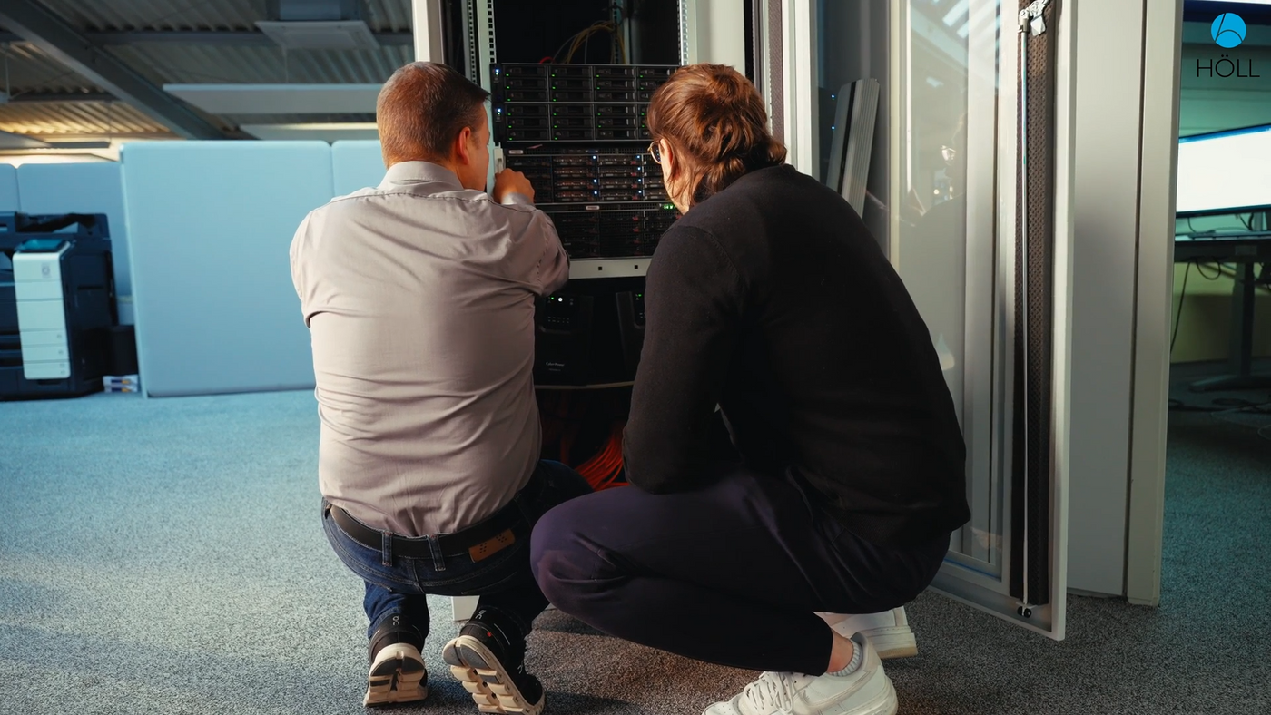 Zwei Techniker knien vor einem geöffneten Serverschrank